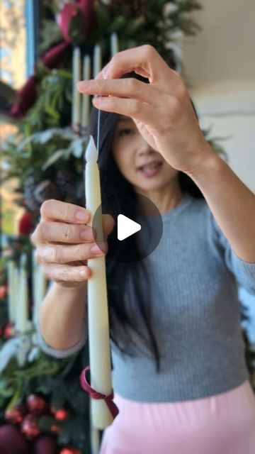 a woman holding a knife in front of a christmas tree