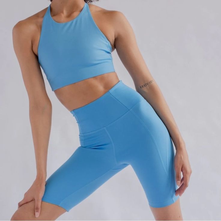 a woman in blue sports bra top and leggings with her hands behind her back