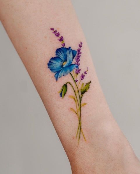 a blue flower tattoo on the right arm and foot with purple flowers around it,