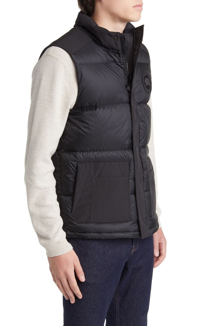 Weather it all in comfort and warmth wearing this vest featuring dual-entry pockets, a webbing grab strap at the upper back and 625-fill-power down insulation. 28" length (size Medium) Storm placket Stand collar Durable water-repellent (DWR) finish Lined, with 625-fill-power down 100% polyamide with 84% polyester, 16% cotton contrast Dry clean Made in Canada Casual Nylon Vest With Side Pockets, Sleeveless Down Puffer Vest, Black Nylon Vest With Functional Pockets, Sleeveless Black Down Outerwear, Functional Down Vest For Winter, Quilted Black Nylon Vest, Black Quilted Nylon Vest, Utility Black Nylon Vest, Black Quilted Outdoor Vest