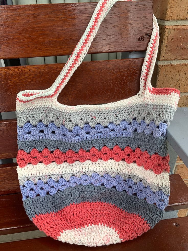 a crocheted purse sitting on top of a wooden bench