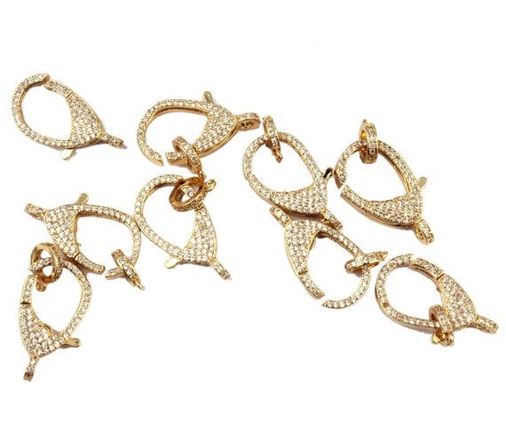 four pairs of gold tone earrings with white diamonds on them, set against a white background