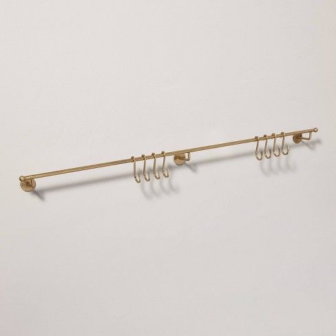 a metal rack with five hooks and four clips on the end, hanging from a white wall