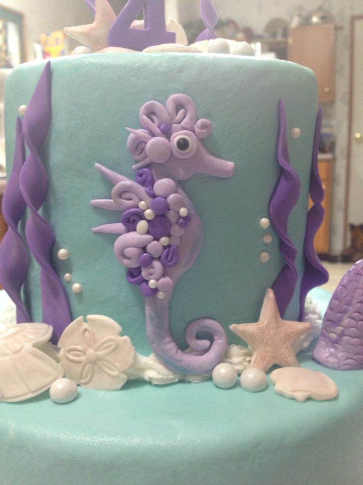 there is a blue and purple cake with seahorses on the top, starfish in the bottom