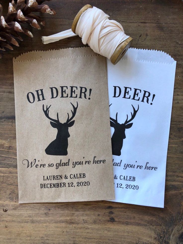 two bags with deer on them sitting next to a spool of twine and pine cones