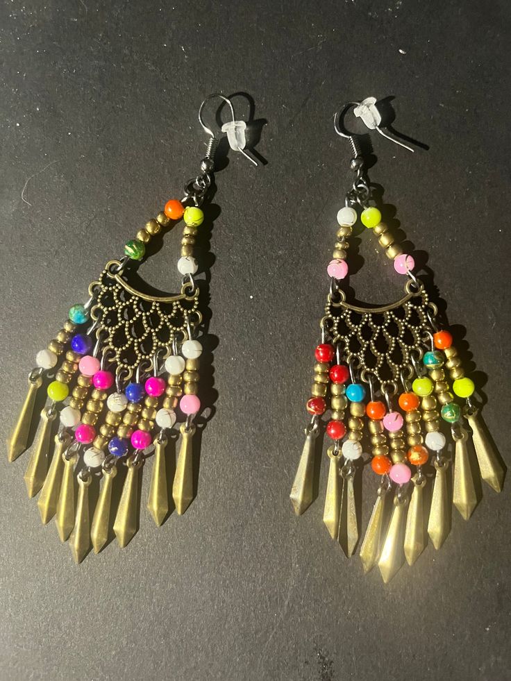 Bronze filigree shape with multi colored beads and beads on dangling posts on black fish hooks with backings. Multicolor Metal Dangle Chandelier Earrings, Multicolor Metal Chandelier Earrings, Colorful Beaded Dangling Earrings For Party, Colorful Dangling Beads Earrings For Party, Bohemian Beaded Danglers For Party, Multicolor Metal Earrings With Dangling Beads, Colorful Dangle Beaded Earrings, Bohemian Multicolor Metal Danglers, Metal Beaded Dangle Earrings