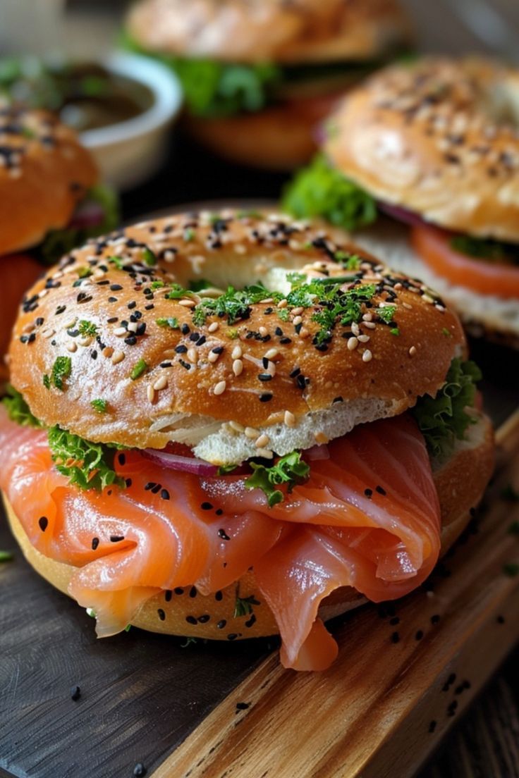 bagel sandwiches with salmon, lettuce and other toppings on a cutting board