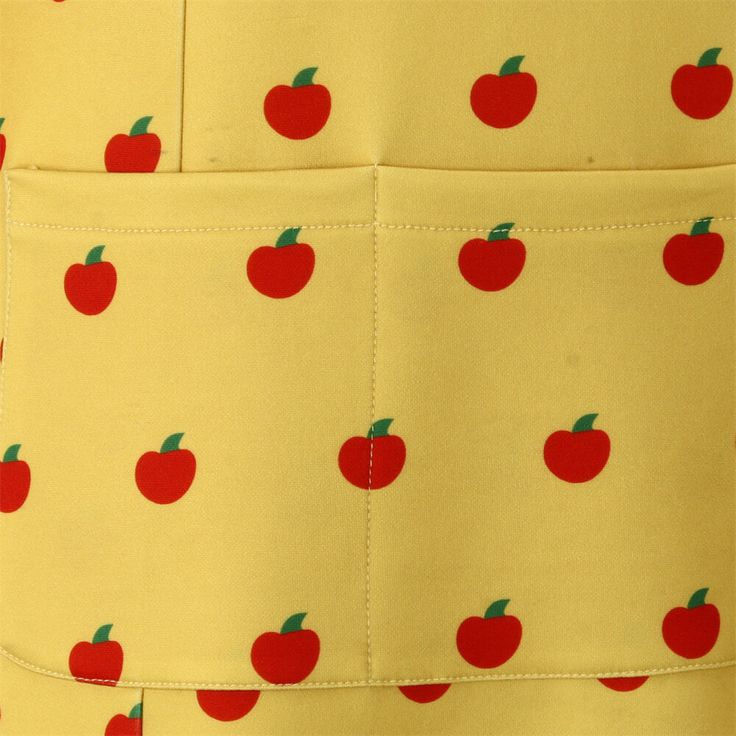 an apron with red apples and green leaves on yellow fabric, as well as white background