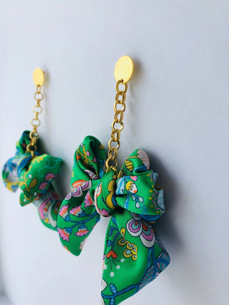 A bold, fun and colourful statement dangle earring featuring an oversized silk bow suspended from a gold plated rolo chain. Available in a variety of beautiful Liberty prints and also available as a regular size.  Each earring set is designed and handmade by myself in my Dartmoor Devon studio, UK Material 100% silk Liberty print bow Chain: Gold plated rolo chain  Available in 5 beautiful Liberty print options (Please see my other listings). Measurements Length (whole earring): Approx 9cm Bow Wid Chic Handmade Green Jewelry, Playful Green Earrings For Party, Playful Green Earrings For Parties, Chic Green Earrings, Bold Green Earrings For Gift, Bold Green Earrings For Gifts, Chic Green Earrings For Gift, Chic Green Jewelry For Gifts, Chic Multicolor Earrings Gift