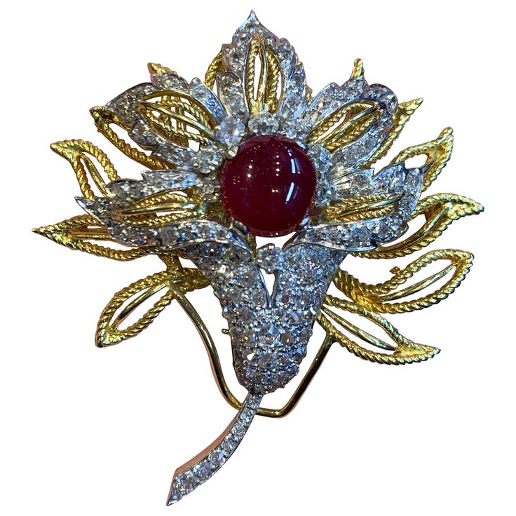 Cabochon Ruby & Diamond Floral Brooch 1 Cabochon Ruby surrounded by 108 antique cut diamonds all set in yellow and white gold. Measurements: 2.5" long Formal Diamond Flower Brooch, Diamond Flower Brooch For Formal Occasions, Luxury Diamond Brooch With Rose Cut Diamonds, Luxury Anniversary Brooches With Cabochon, Luxury Cabochon Brooches For Anniversary, Luxury Yellow Gold Cabochon Brooches, Ornate Diamond Brooches For Formal Occasions, Formal Flower Shaped Hallmarked Brooch, Exquisite Diamond Brooches In Yellow Gold