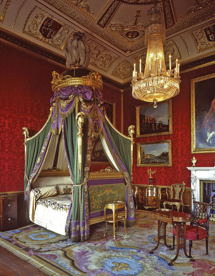 an ornate bedroom with red walls and paintings on the wall, including a canopy bed