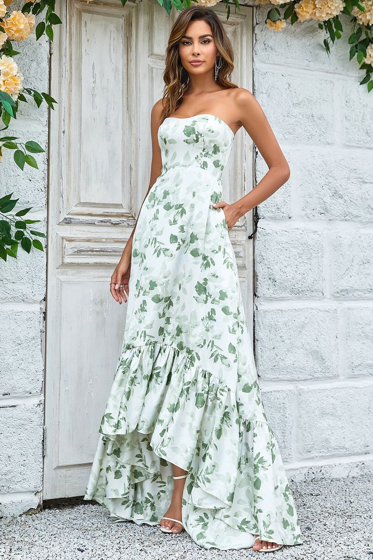 a woman standing in front of a door wearing a white dress with green flowers on it