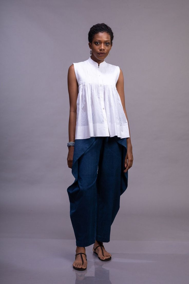 White organic cotton button down sleeveless woman's top with mandarin collar, pleated front and textured back. Geometric folds are created on fabric using  the technique of shadow folding, which is made from a single three step process. The flexible property of the organic cotton allows pleats to be folded to augment and give a dimensionality not present in a flat surface; and the translucent quality adds a unique intricacy to the geometric patterns. When lines in a pattern are folded as pleats, Chic Sleeveless Cotton Shirt, Summer Relaxed Fit Top With Pintucks, Cotton Sleeveless Blouse For Work, Sleeveless Relaxed Fit Shirt For Spring, Relaxed Fit Sleeveless Shirt For Spring, Cotton Tops With Pintucks And Relaxed Fit, Fitted Cotton Blouse For Summer, Relaxed Fit Cotton Tops With Pintucks, Cotton Sleeveless Blouse For Spring