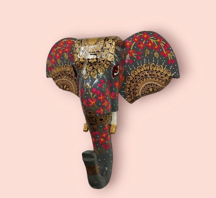 an elephant head with ornate designs on it's face, against a pink background