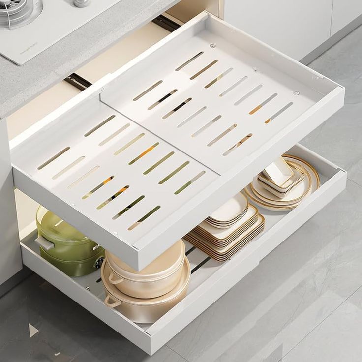 an open drawer in a kitchen filled with dishes