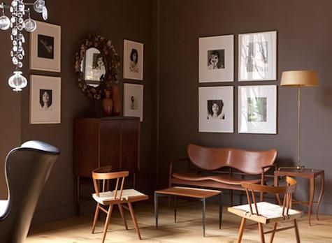 a living room filled with lots of furniture and pictures on the wall next to a chair