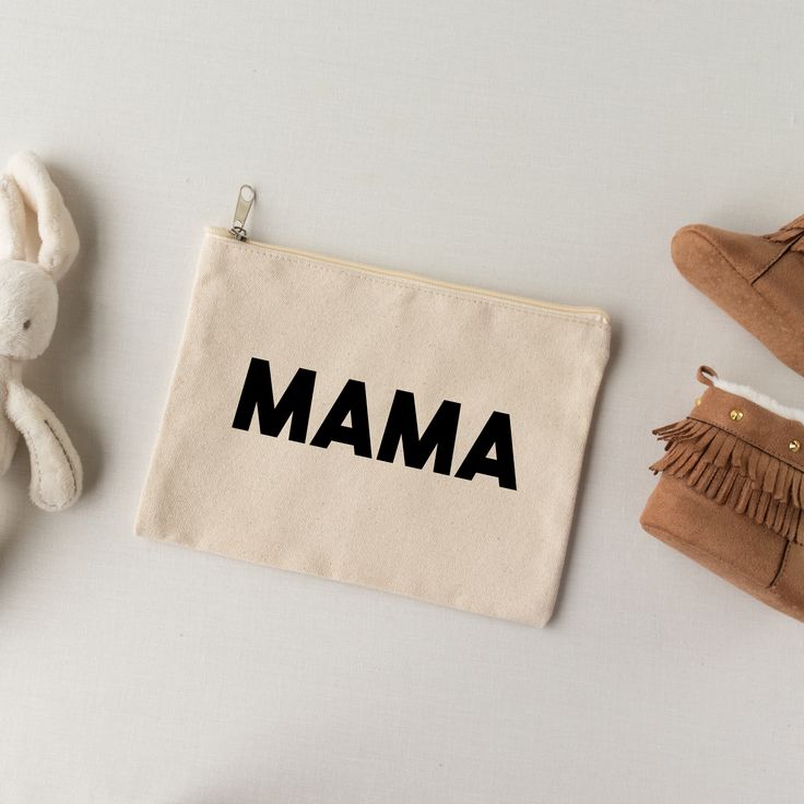 a small pouch with the word mama on it next to two stuffed animals