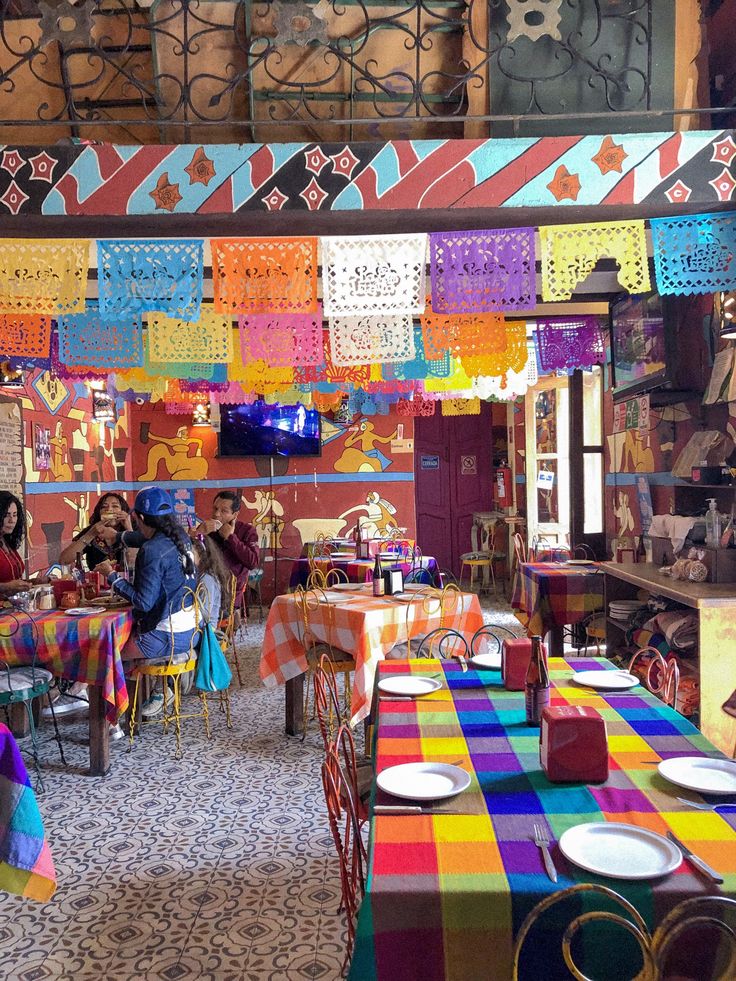 people are sitting at colorful tables in a restaurant