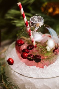 a glass ornament with candy canes and cherries in it on top of ice