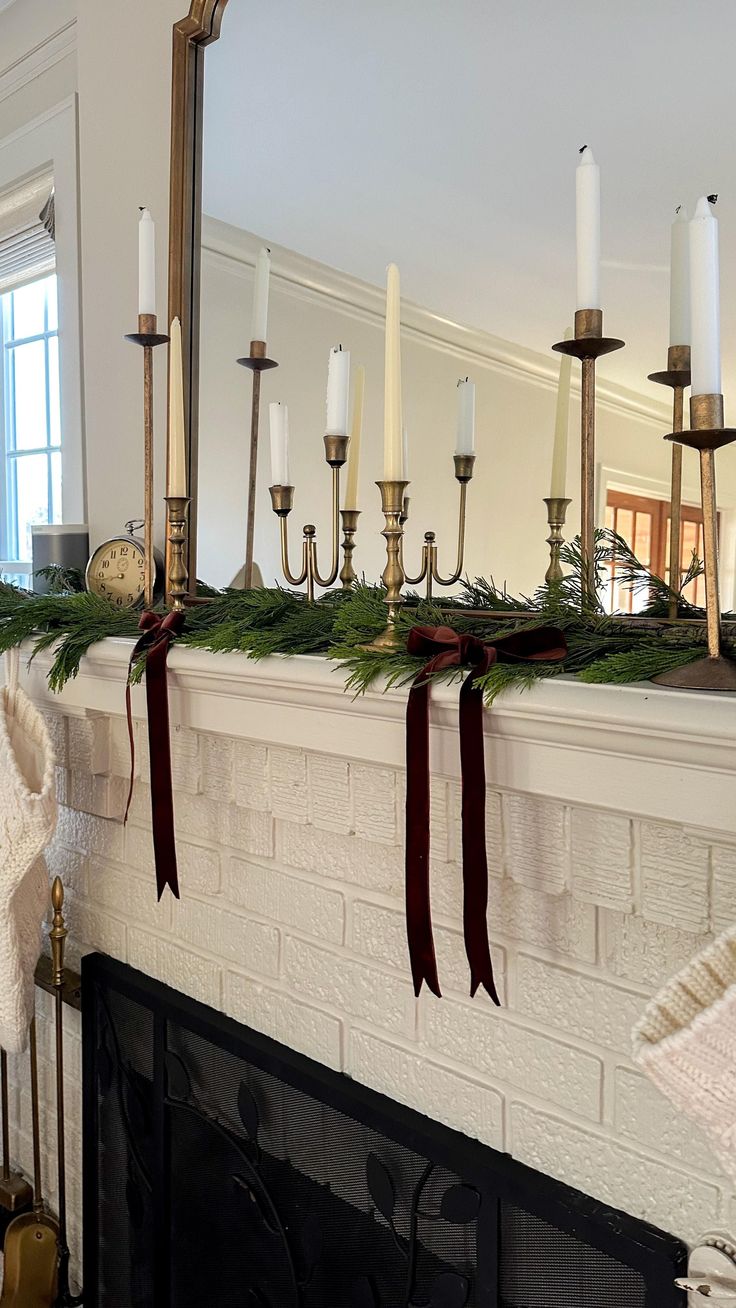 a mantel with candles, stockings and other christmas decorations on it in front of a mirror