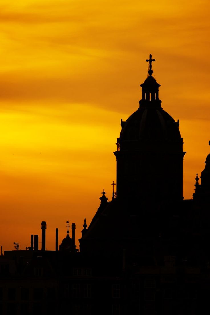 the silhouette of a church steeple against an orange sky