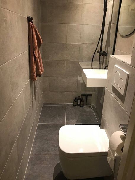 a bathroom with two sinks, a toilet and a shower head mounted to the wall