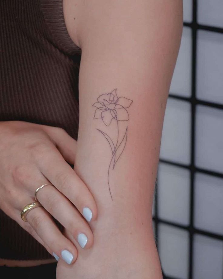 a woman's arm with a small flower tattoo on the left side of her arm