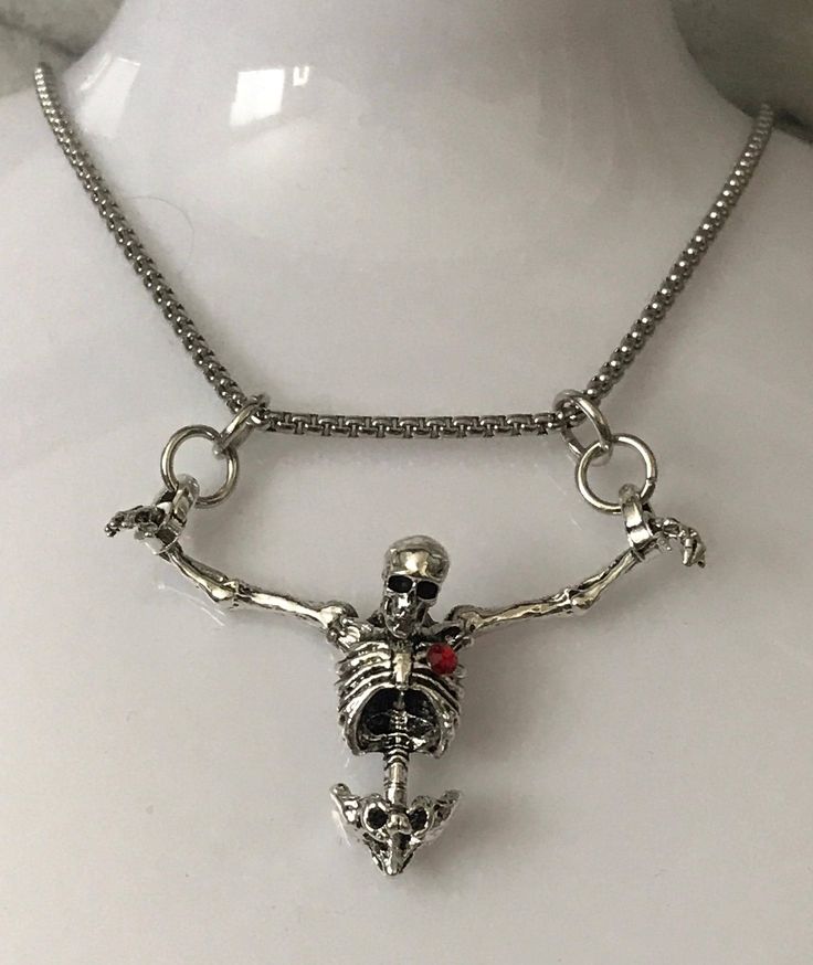 Embrace the darker side of fashion with our Hanging Skeleton Torso Necklace on a stainless steel 18" chain. This unique piece features a silver skeleton hanging from both wrists, adding a touch of Gothic flair to any outfit. You have the option to personalize your necklace by choosing between a skeleton with or without a striking red rhinestone heart accent. The skeleton's head is elegantly tilted forward, enhancing its macabre charm. Perfect for Halloween or as a statement accessory, this necklace comes beautifully presented in a sleek black gift box, making it an ideal gift for those who appreciate edgy and distinctive jewelry pieces. Edgy Clavicle Chain Jewelry Gift, Edgy Clavicle Chain Jewelry For Gift, Edgy Chain Jewelry Gift, Edgy Chain Jewelry As Gift, Edgy Chain Jewelry For Gifts, Gothic Stainless Steel Silver Chain Jewelry, Edgy Chain Jewelry For Gift, Edgy Adjustable Chain Necklace For Gifts, Heart-shaped Metal Jewelry For Halloween