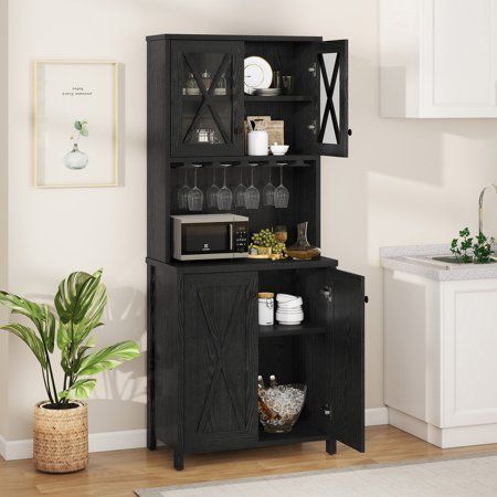 a black cabinet with wine glasses on it in a living room next to a potted plant