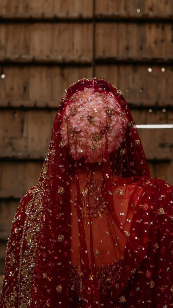 the back of a woman's head wearing a red veil with flowers on it