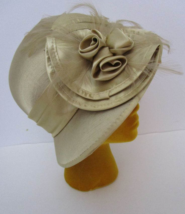 "Art Deco gold satin bucket church hat made from Swan Hat New York. Close fitting, rigid rounded dome crown and medium down turned brim.  Intricately folded Art Deco influenced satin band and floral medallion. Sheer feathers tucked in too. The inside of the hat is gorgeous, entirely covered in satin with drawstring to secure. Choosing vintage and preowned is a simple sustainable way you can reuse recycle repurpose for a healthier Mother Earth. Condition:  Very good vintage condition, slightest s Gold Wide Brim Mini Hat For Evening, Gold Wide Brim Hat For Evening, Gold Hats For Church And Royal Ascot, Gold Curved Brim Costume Hat For Evening, Gold Brimmed Mini Hat For Formal Events, Gold Brimmed Mini Hat For Formal Occasions, Gold Wide Brim Mini Hat For Royal Ascot, Gold Costume Hat With Short Brim For Kentucky Derby, Gold Costume Hat With Curved Brim For Evening