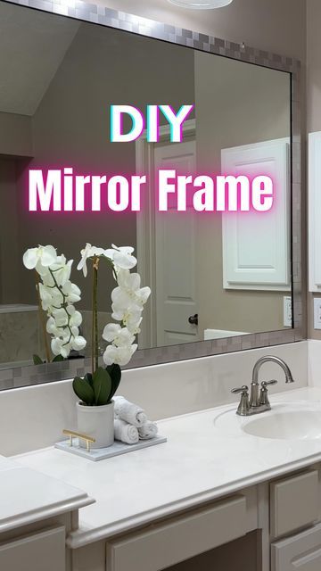 a bathroom with a large mirror over the sink and flowers on the counter in front of it