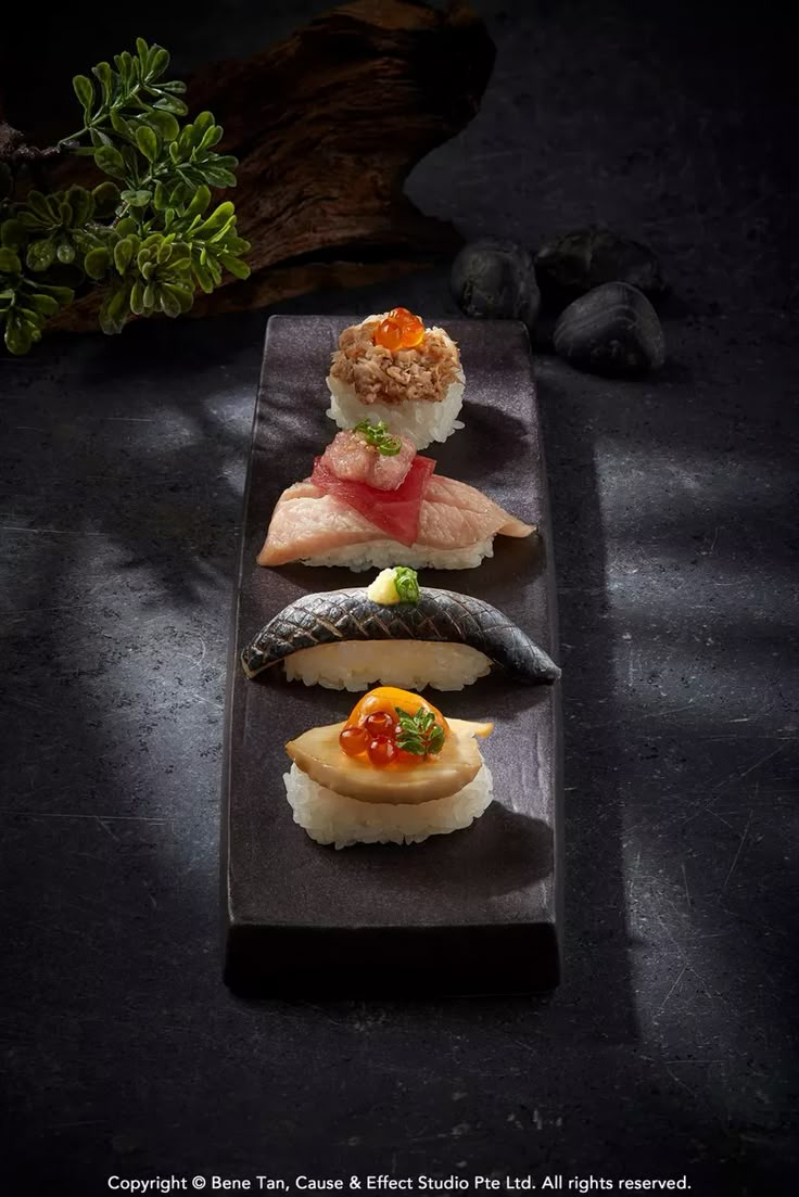 three sushi dishes are arranged on a black plate