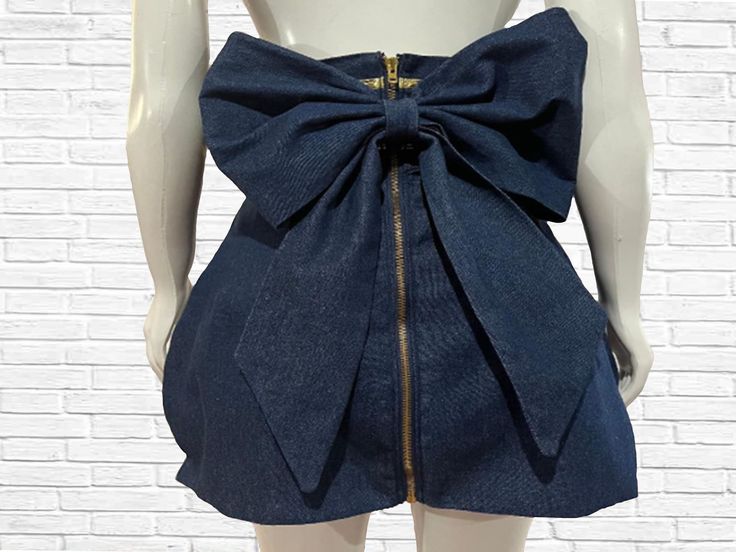 "This fun twist on your denim skirt features a high waistband trimmed with metallic gold bias tape, a mini tulip shaped bottom and is finished off with a large center back bow to add a bit of high fashion drama. From waist to hem the skirt measures 20\" long Zipper color may change ( silver or gold ) depending on availability.  There are two available. One small and one medium PLEASE view size chart provided before placing your order There are no returns on this custom item, even exchange or merchandise credit only." High Waist Denim Skirt, Bow Jeans, Skirt With Bow, Skirt Bow, Jean Mini Skirt, Bow Skirt, High Waisted Denim Skirt, Jean Mini Skirts, High Waist Denim