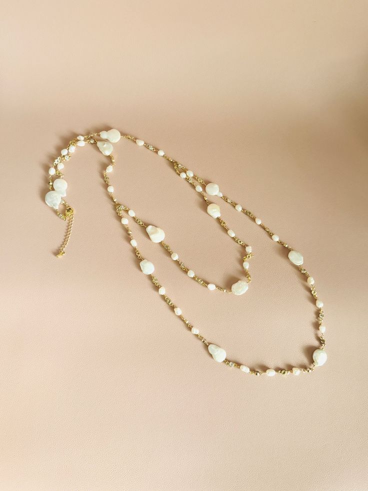 Introducing our most dreamy bridal necklace! A delicate gold chain adorned with freshwater baroque pearls and cubic zirconia forms a boho-inspired lariat necklace. Wear it in the front or back, and a backdrop option is also available if needed. **Custom necklace available** 🖤 M A T E R I A L S  *  A N D  *  S I Z E  🖤 ❇️ MATERIAL & METAL: Brass- Freshwater Pearl/Cubic Zirconia ❇️ METAL PLATING: Gold ❇️ ESTIMATED NECKLACE SIZE: (1st layer) 26.5-inch (2nd layer) 20-inch + 2-inch Extension ❇️ ESTIMATED BACKDROP SIZE: 11.5-inch ❇️ QUANTITY: 1pcs/1pairs ❇️ LEAD-FREE & NICKEL FREE 🖤 A V A I L A B L E  *  F I N I S H 🖤 ❇️NECKLACE ❇️NECKLACE & BACKDROP  🖤 C U S T O M I Z I N G  *  A N  *  E X I S T I N G  *  P I E C E 🖤 If you love this piece but feel you would like to make a few changes or Gold Backdrop Necklace With Pearl Drop, Gold Long Backdrop Necklace For Wedding, Delicate Beaded Chain Necklace For Wedding, Delicate Beaded Necklace For Wedding, Gift Baroque Pearl Beaded Chain Jewelry, Elegant Cream Jewelry With Beaded Chain, Delicate Wedding Beaded Necklaces, Delicate Wedding Beaded Necklace, Single Strand Baroque Pearl Necklaces For Wedding