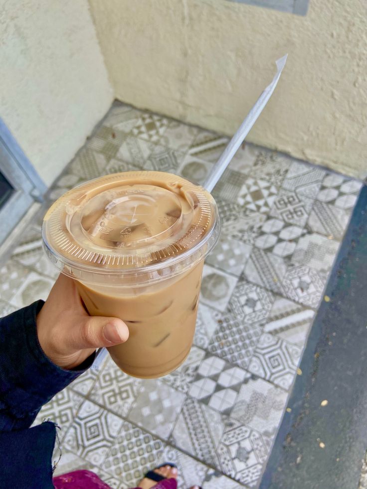 a person holding up a drink with a knife sticking out of it