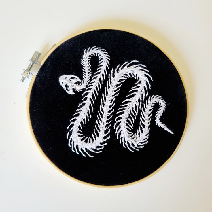 a black and white embroidered wall hanging with a snake on it