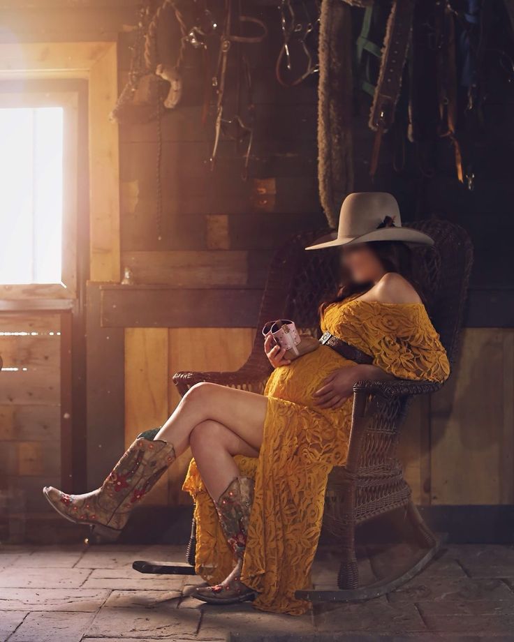 a woman in a yellow dress sitting on a chair with her legs crossed and wearing cowboy boots