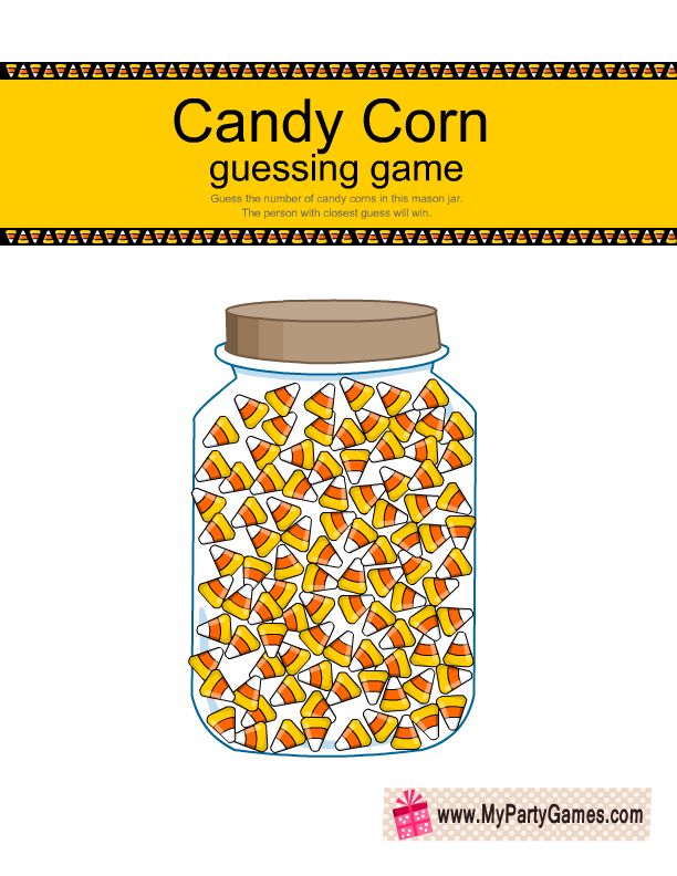 a jar filled with candy corn on top of a white table next to a yellow sign