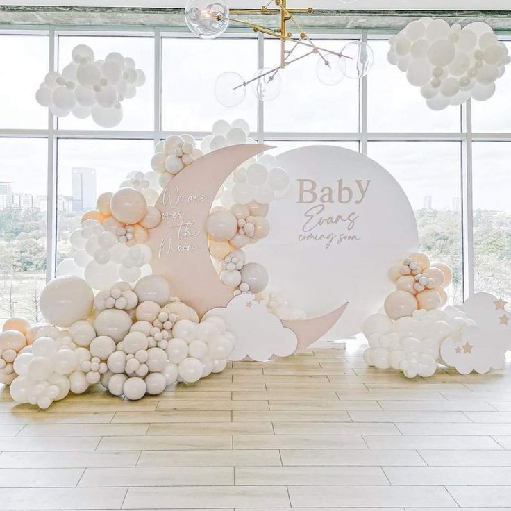 a baby shower with balloons, moon and clouds on the floor in front of a large window