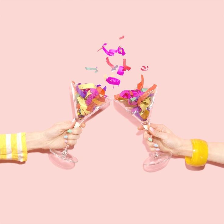 two people holding up wine glasses filled with confetti