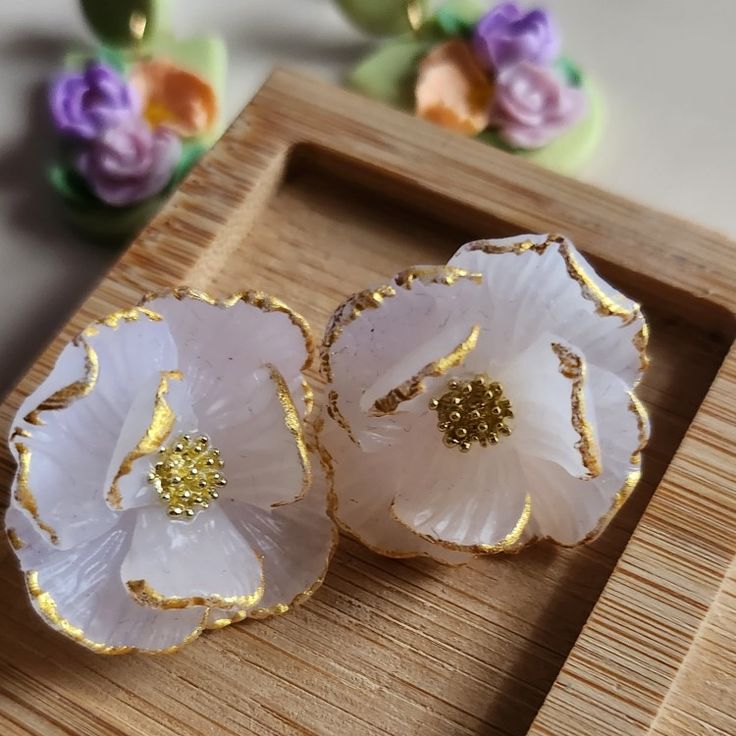 two white flowers sitting on top of a wooden tray