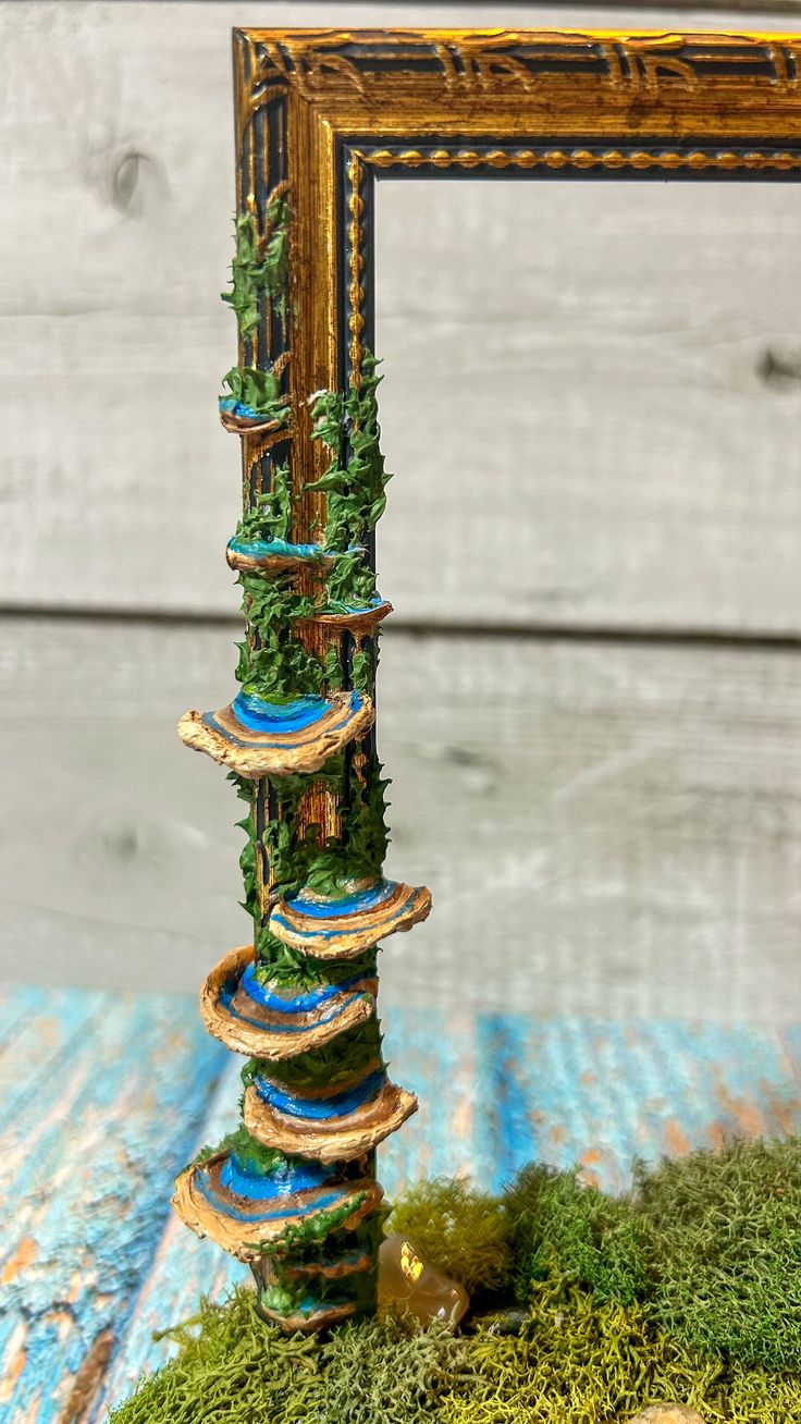 a tall tower made out of rocks and moss on top of a wooden table next to a mirror