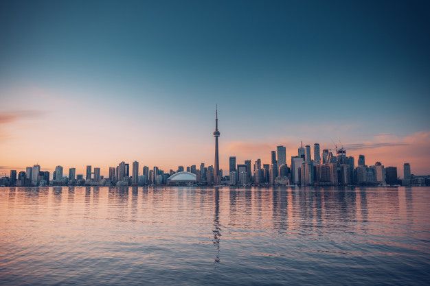 the city skyline as seen from across the water at sunset in toronto, on a clear day