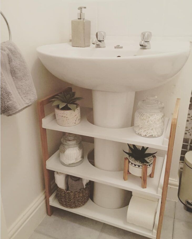 a white sink sitting under a bathroom mirror next to a shelf filled with toiletries