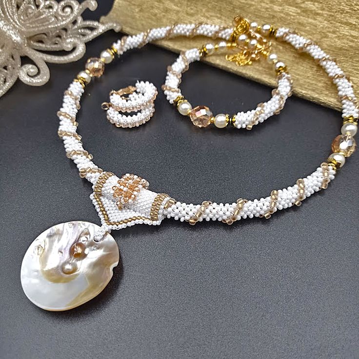 "This is a handmade jewelry set. Consists of a choker necklace with a natural shell Birth of Venus shell and freshwater pearl pendant. The set includes a beaded bracelet on memory wire and huggie hoop earrings. This homemade jewelry will perfectly complement your image and emphasize your style. It also makes a wonderful gift for a woman. Size. Necklace length is about 17,3 inc. (44 cm) with a clasp. Material - Czech and Japanese beads, faceted Czech glass beads, and glass pearls. Accessories - u Handmade Elegant Shell Necklace, Handmade Elegant Round Shell Necklace, Elegant Handmade Round Shell Necklace, Handmade Elegant Pearl White Shell Necklace, Elegant Shell Beaded Necklaces With Round Beads, Handmade Shell Jewelry For Wedding, Handmade Round Shell Jewelry, Handmade Mother Of Pearl Round Necklace, Handmade Mother Of Pearl Necklace