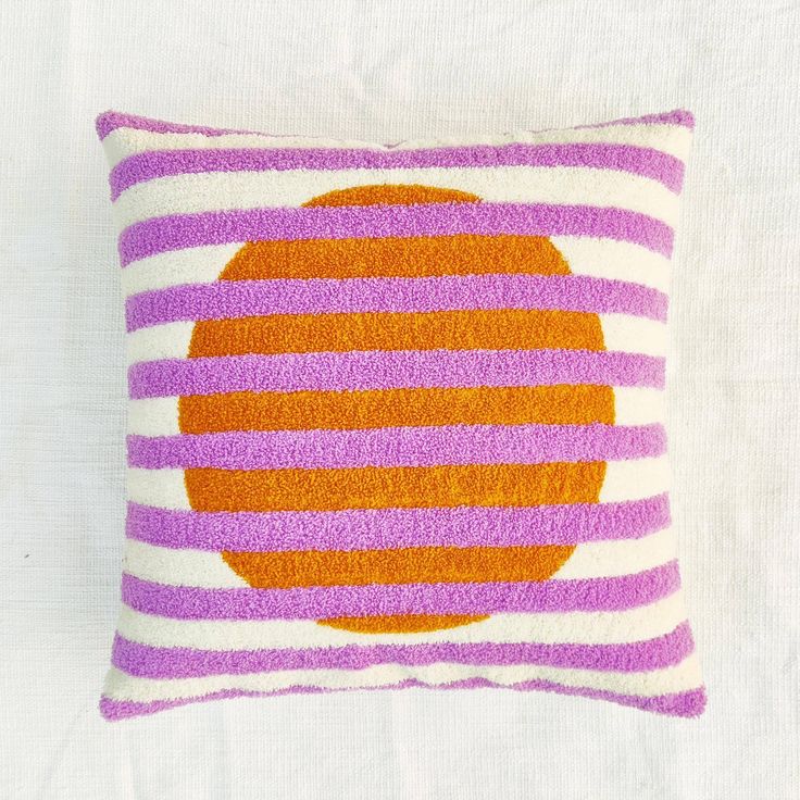 an orange and purple striped pillow on a white background