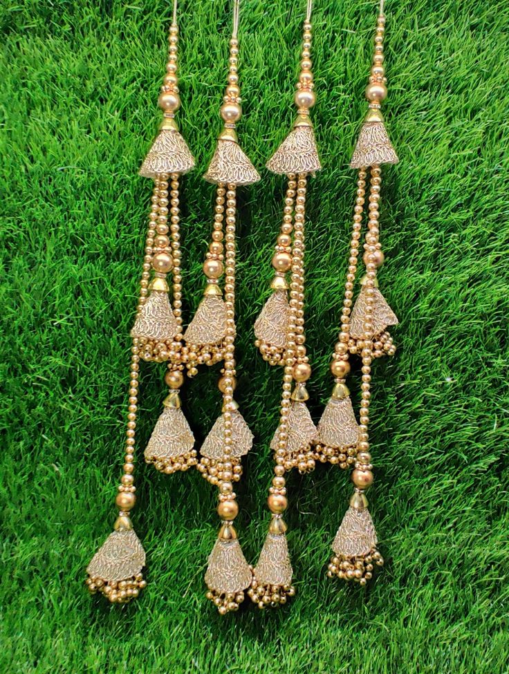 several gold colored beads hanging from the side of a green grass covered field with small white and