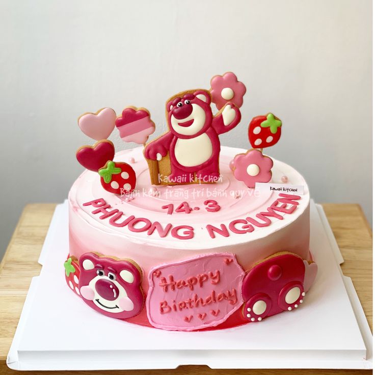 a pink birthday cake decorated with teddy bears and hearts