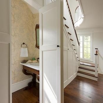 an open door leading to a bathroom and stairway in a house with wood floors, white walls and wooden stairs